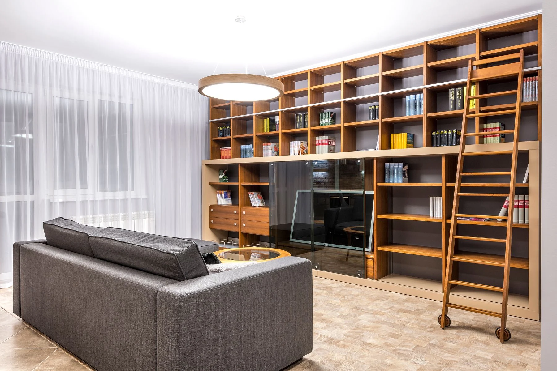 Eine raumhohe Holzbibliothek mit Leiter im Wohnzimmer